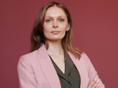 Elegant businesswoman with arms crossed in studio portrait, showcasing leadership and confidence.